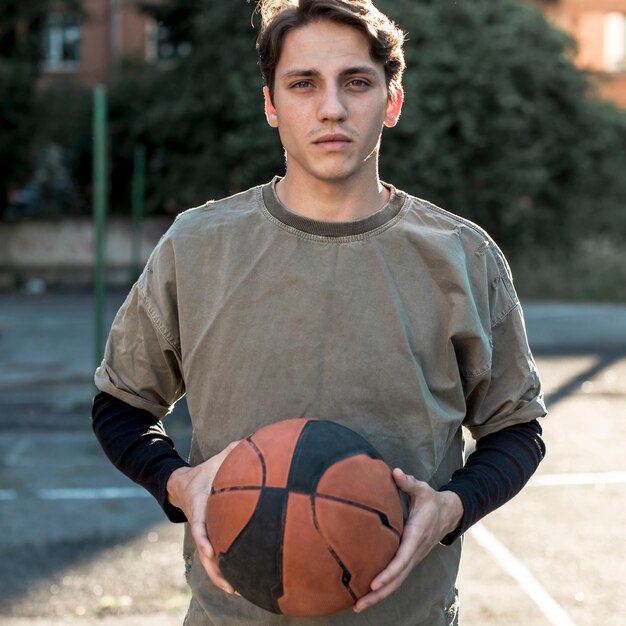Tiro medio hombre sosteniendo una pelota de baloncesto