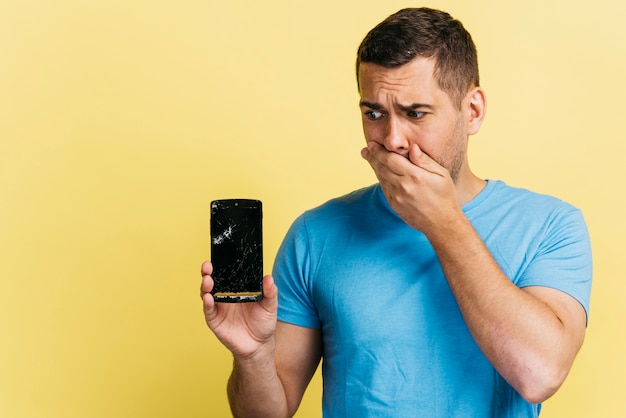 Foto gratuita tiro medio hombre sosteniendo un teléfono roto