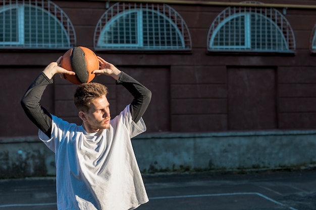 Foto gratuita tiro medio hombre tirando una pelota de baloncesto