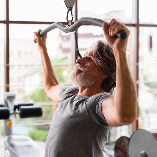 Foto gratuita tiro medio hombre trabajando en el gimnasio