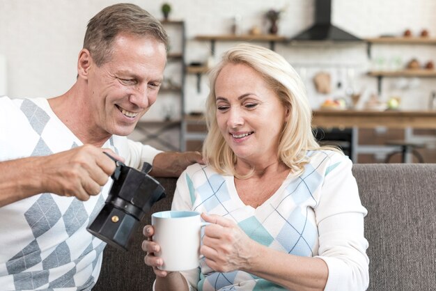 Tiro medio hombre vertiendo café a mujer