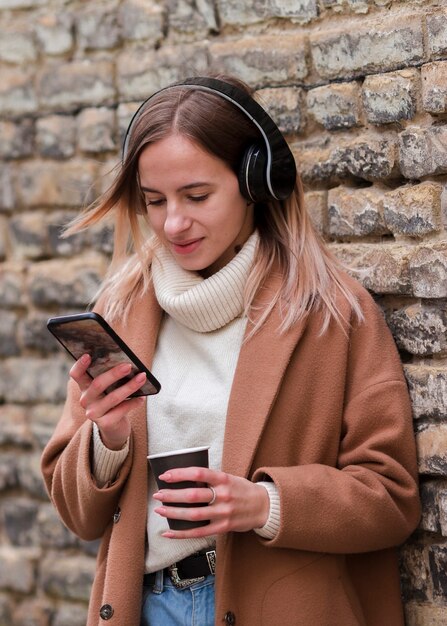Tiro medio joven mujer rubia escuchando música con auriculares