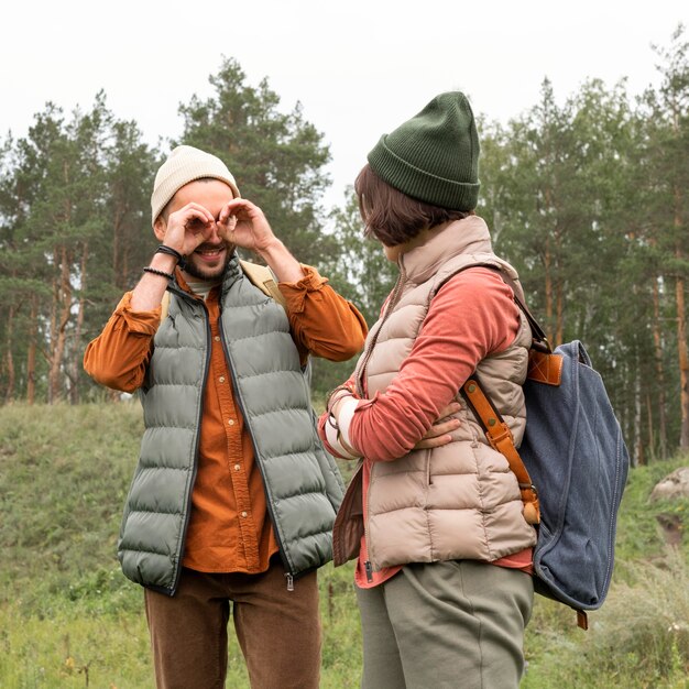 Tiro medio joven pareja jugando en la naturaleza