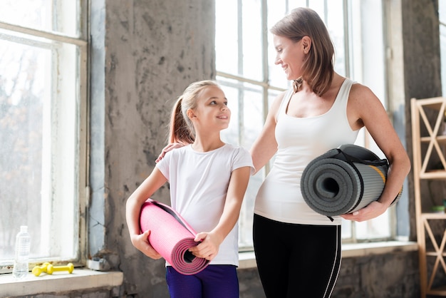 Foto gratuita tiro medio, madre e hija con colchonetas de yoga