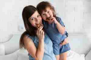 Foto gratuita tiro medio, madre e hija comiendo galletas de chocolate