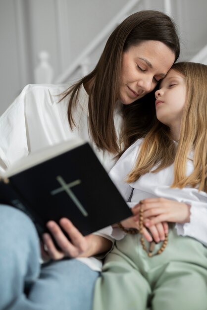 Tiro medio madre y niña con biblia.