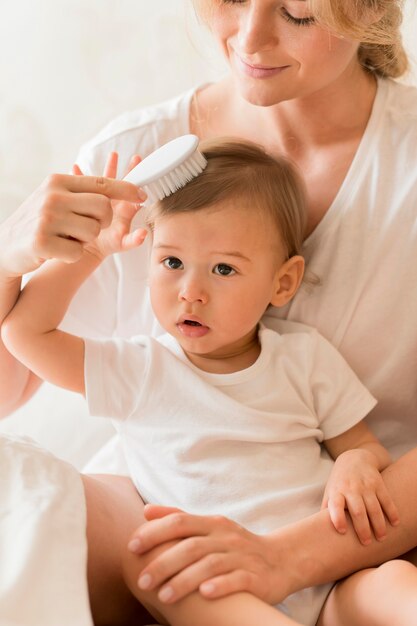 Tiro medio mamá cepillando el pelo del bebé