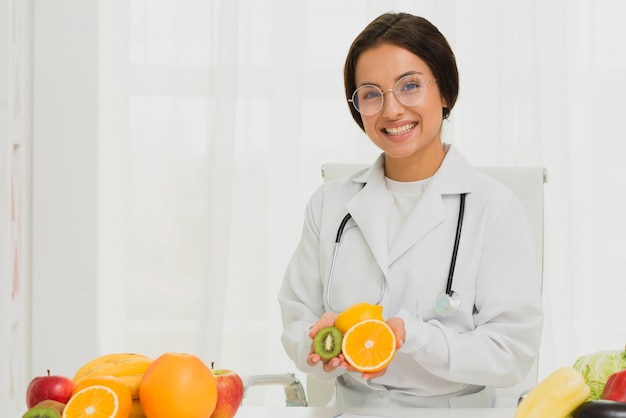 Tiro medio médico feliz con naranja y kiwi