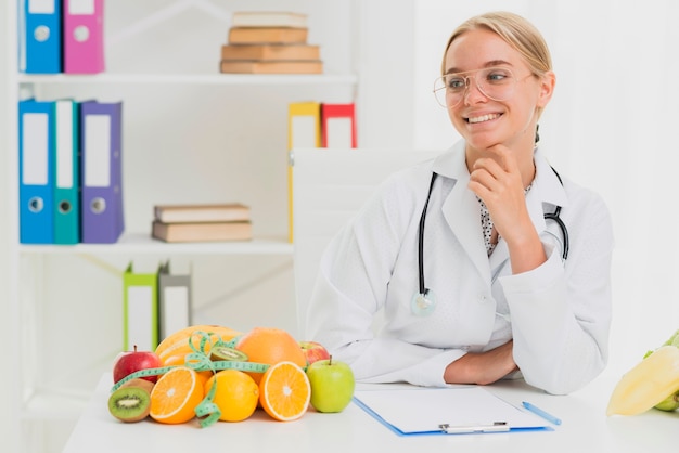 Tiro medio médico sonriente con frutas saludables