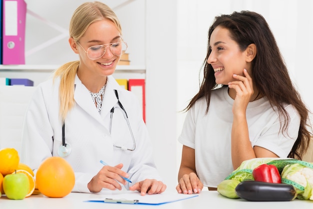 Tiro medio médico sonriente y paciente hablando