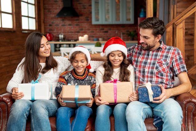 Foto gratuita tiro medio a miembros de la familia con regalos en el sofá