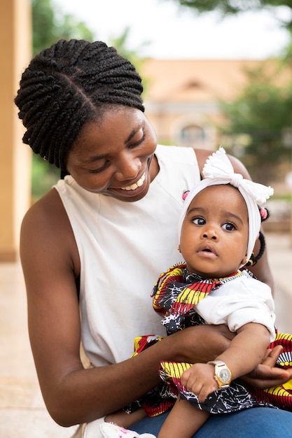 Tiro medio mujer africana sosteniendo niña