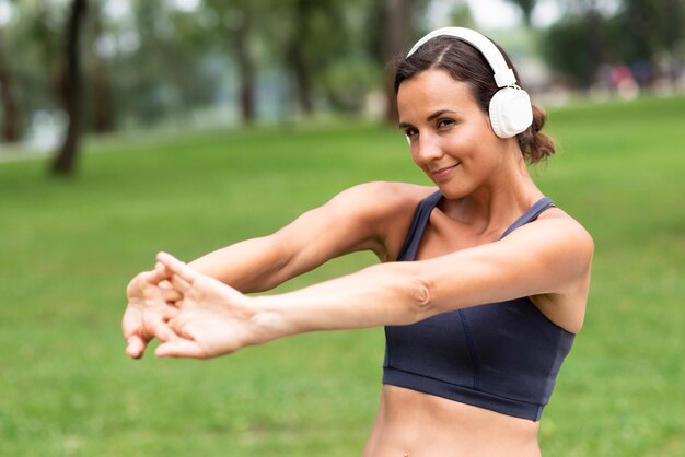 Tiro medio mujer con auriculares estirando los brazos