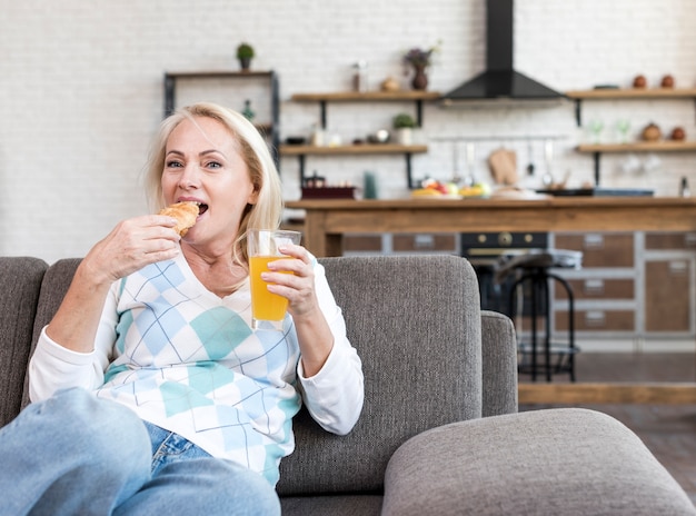 Tiro medio mujer comiendo en el sofá