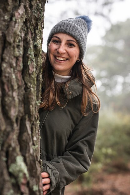 Tiro medio mujer detrás de un árbol