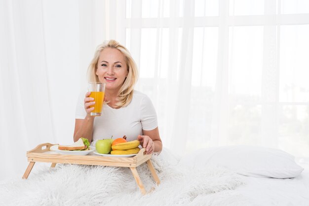 Tiro medio mujer feliz bebiendo jugo de naranja