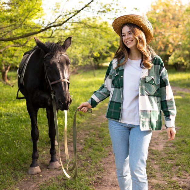 Tiro medio mujer feliz y caballo al aire libre