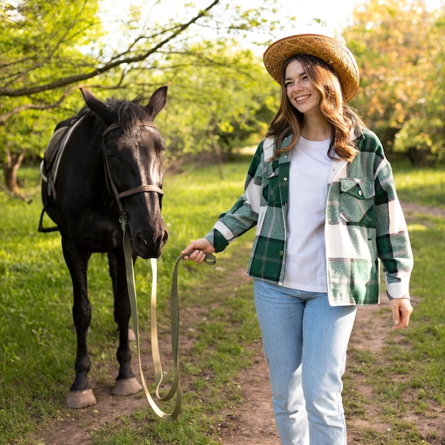 Tiro medio mujer feliz y caballo al aire libre