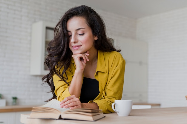 Tiro medio mujer feliz leyendo en la cocina