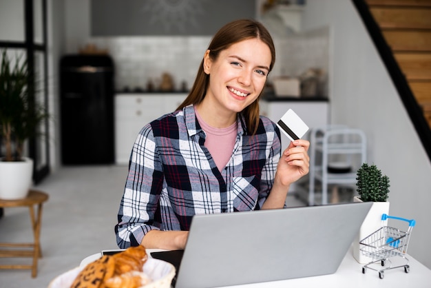 Tiro medio mujer feliz mostrando tarjeta de crédito