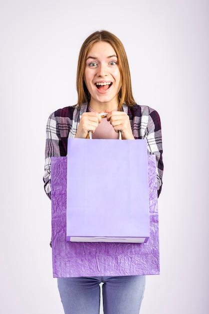 Foto gratuita tiro medio mujer feliz sosteniendo bolsas y mirando a cámara