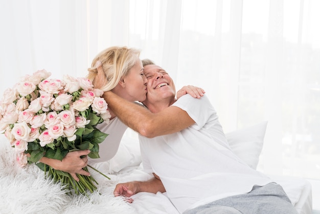 Tiro medio mujer con flores besando a hombre