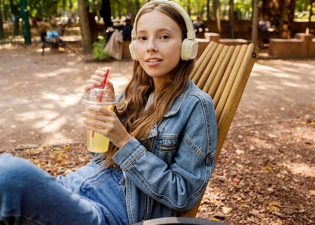 Tiro medio mujer joven con auriculares sosteniendo jugo fresco