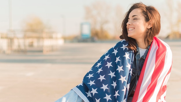 Tiro medio mujer joven con gran bandera de Estados Unidos