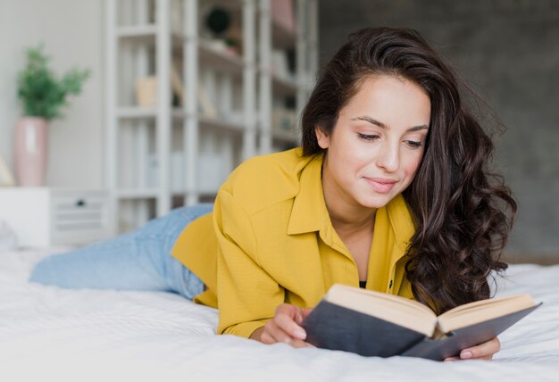 Tiro medio mujer leyendo en el dormitorio