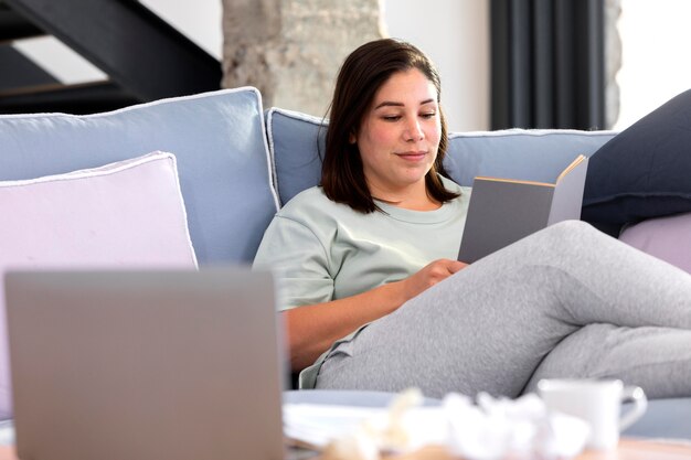 Tiro medio mujer leyendo en el sofá