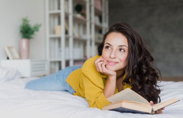 Tiro medio mujer con libro mirando a otro lado