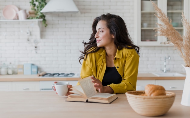 Tiro medio mujer con libro y taza de café