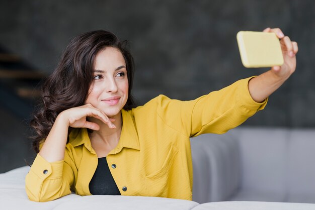 Tiro medio mujer morena tomando un teléfono