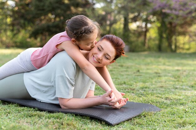 Tiro medio mujer y niña en estera de yoga