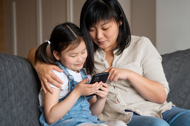 Tiro medio mujer y niña con teléfono