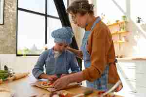Foto gratuita tiro medio mujer y niño cocinando juntos