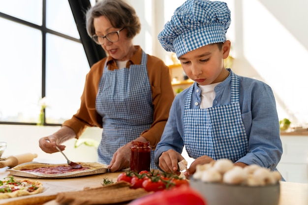 Tiro medio mujer y niño cocinando juntos