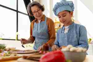 Foto gratuita tiro medio mujer y niño cocinando juntos