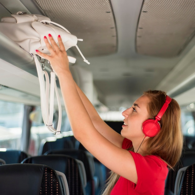 Tiro medio mujer poniendo mochila en la rejilla del bus