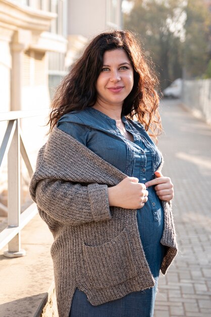 Tiro medio mujer posando al aire libre durante el embarazo