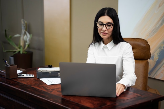 Tiro medio mujer que trabaja en la computadora portátil