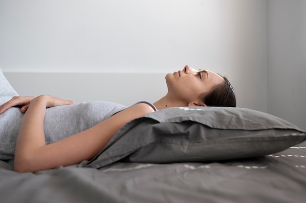 Tiro medio mujer recostada sobre la almohada