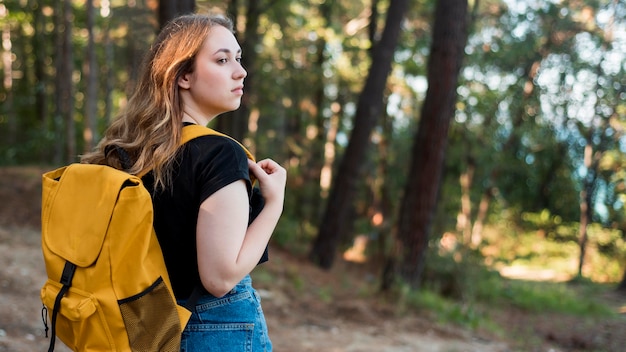 Tiro medio mujer rubia con mochila en el bosque