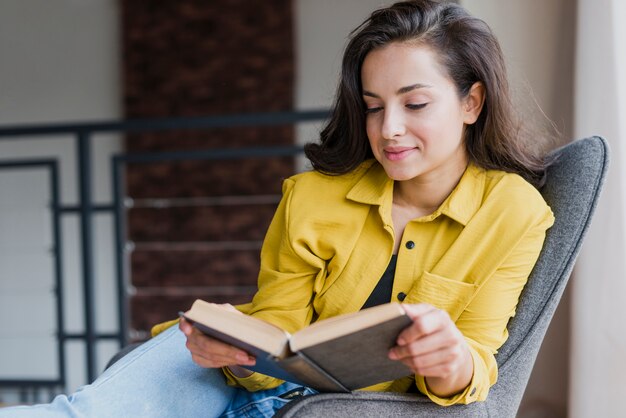 Tiro medio mujer sentada y leyendo