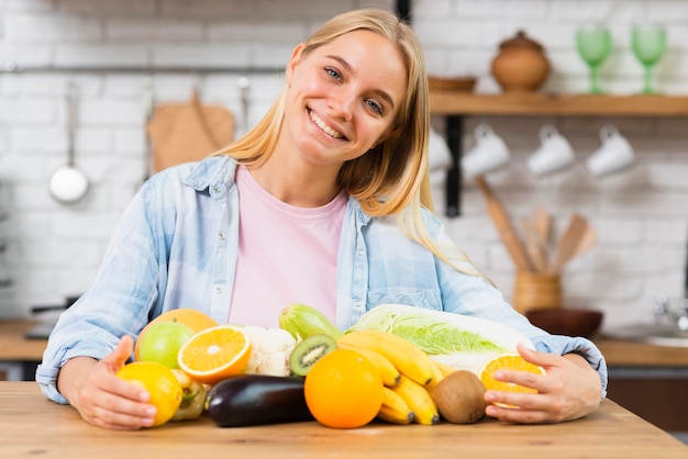 Tiro medio mujer sonriente con fruta en la cocina