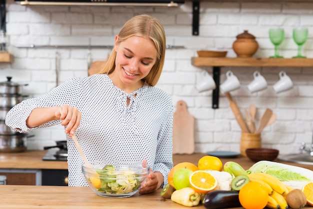 Foto gratuita tiro medio mujer sonriente haciendo una ensalada