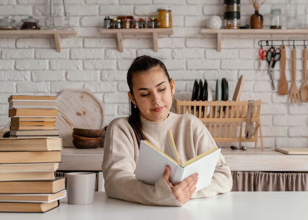 Tiro medio mujer sonriente leyendo en interiores