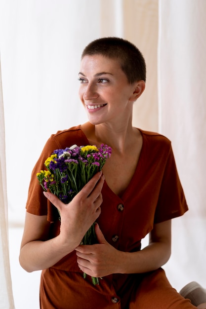 Foto gratuita tiro medio mujer sonriente sosteniendo flores