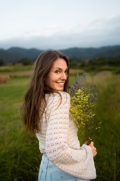 Tiro medio mujer sonriente sosteniendo flores