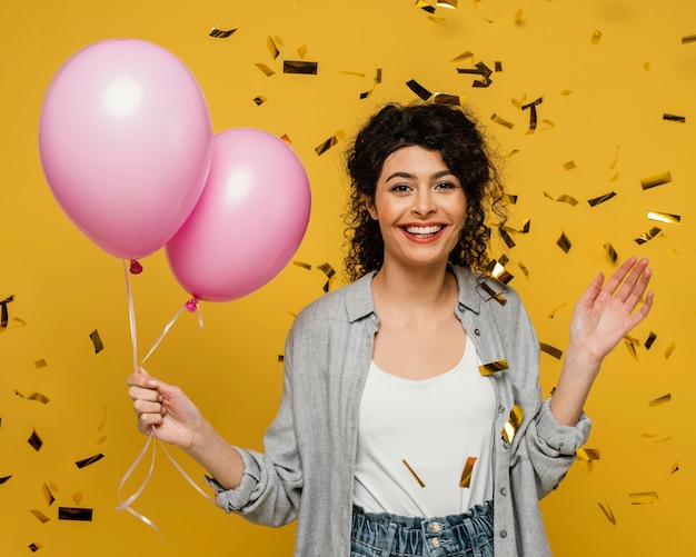 Tiro medio mujer sonriente sosteniendo globos